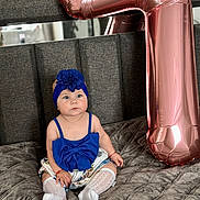 Clara joined the competition — help win amazing prizes! baby, blue_outfit, headband, flower_accessory, balloon, rose_gold, number_seven, bed, gray_bedspread, child, sitting, cute, indoor, portrait, celebration, decor, sock, white_sock, infant, fashion