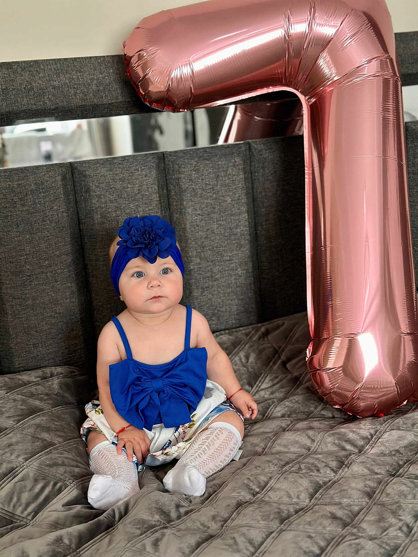 Clara joined the competition — help win amazing prizes! baby, blue_outfit, headband, flower_accessory, balloon, rose_gold, number_seven, bed, gray_bedspread, child, sitting, cute, indoor, portrait, celebration, decor, sock, white_sock, infant, fashion