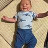 baby, infant, child, smile, happy, blue_clothing, shirt, pants, couch, furniture, indoors, cheeky, face, skin, person, young_child, cute, lying_down, texture, home