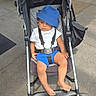 Kashton joined the competition — help win amazing prizes! toddler, stroller, hat, bucket_hat, blue_shorts, white_tshirt, child, barefoot, outdoor, sidewalk, wheels, sunlight, shade, baby, casual, summer, seatbelt, expression, urban, relaxed