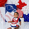 baby, boy, cake, birthday, first_birthday, baseball, balloons, red, white, blue, celebration, smiling, face, hands, floor, decorations, sitting, party, festive, cute