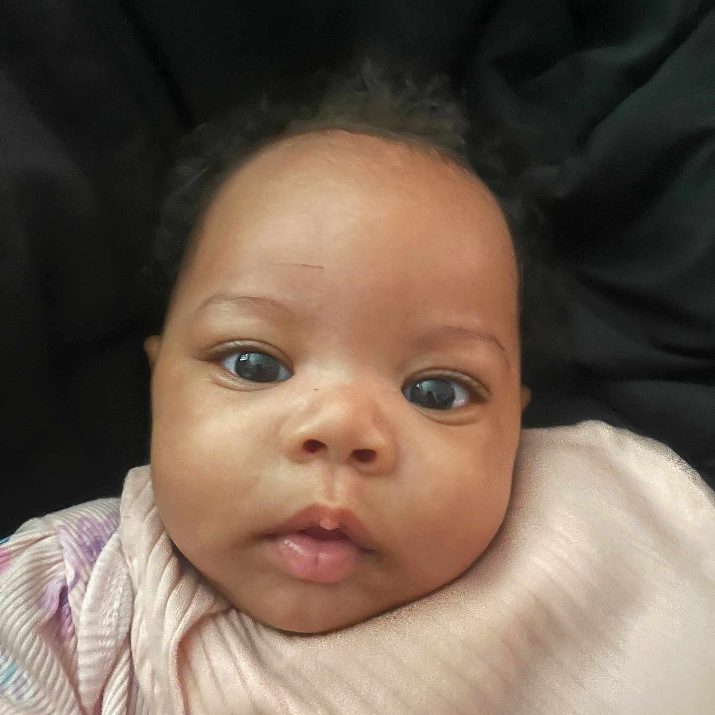 Avah-Grace joined the competition — help win amazing prizes! baby, black_background, child, closeup, curly_hair, cute, expression, eyes, face, head, indoors, infant, looking, newborn, person, pink_clothing, portrait, skin, soft_texture, young_child