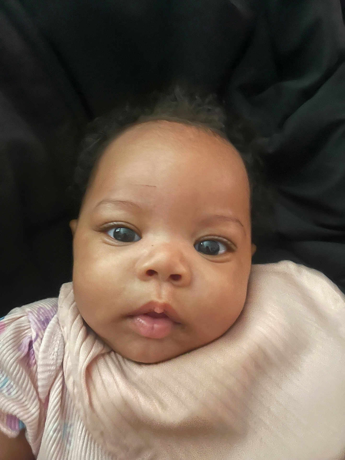 Avah-Grace joined the competition — help win amazing prizes! baby, black_background, child, closeup, curly_hair, cute, expression, eyes, face, head, indoors, infant, looking, newborn, person, pink_clothing, portrait, skin, soft_texture, young_child