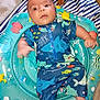 baby, infant, inflatable_ring, swimwear, shark_pattern, sea_creatures, dog_paw, striped_blanket, blue, colorful, cute, child, playful, indoor, person, clothing, sitting, portrait, looking_up, expression