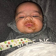 Tommy is registered to the contest to win money with this photo: baby, infant, face, food_smear, blanket, hoodie, sleepy, cozy, indoor, closeup, child, cute, soft_texture, expressionless, lying_down, person, newborn, clothing, resting, comfort