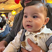 Emilio joined the competition — help win amazing prizes! baby, man, indoor, balloons, lighting, smile, face, hand, clothing, suspenders, beard, curious, warm_light, celebration, portrait, people, holding, event, table, background