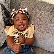 Denver joined the competition — help win amazing prizes! baby, child, smiling, headband, bow, denim_skirt, yellow_top, couch, furniture, happy, cute, indoor, portrait, person, clothing, sitting, infant, hands, skin, face