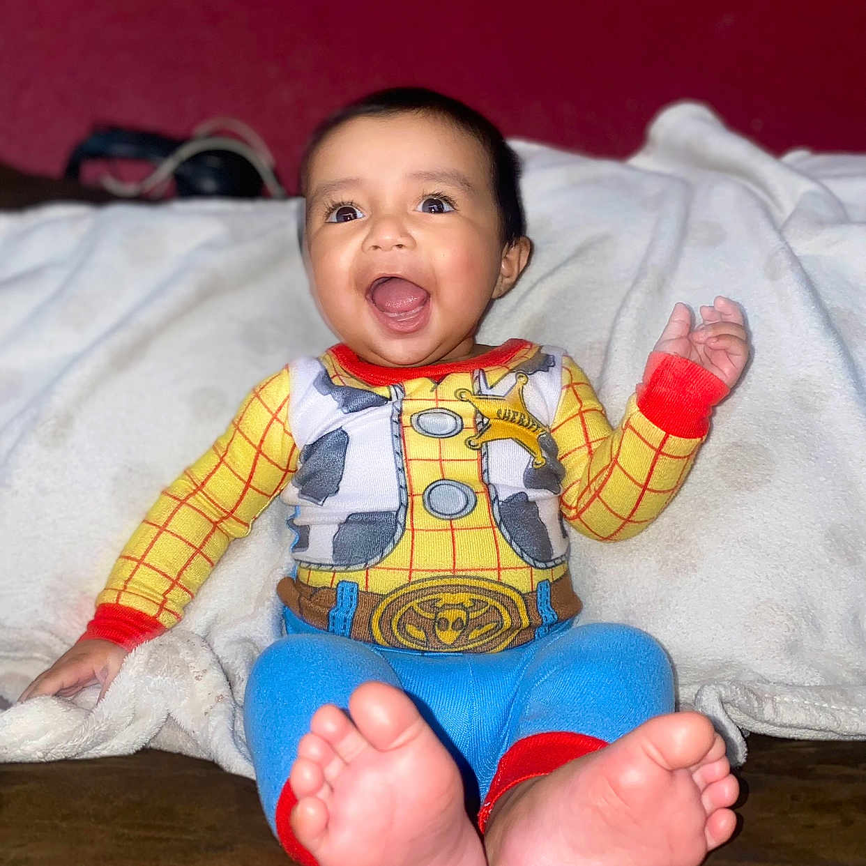 Ernest is registered to the contest to win money with this photo: baby, blanket, child, clothing, colorful, cowboy, cozy, cute, expression, face, feet, happy, indoors, outfit, person, portrait, sitting, smiling, toes, warm