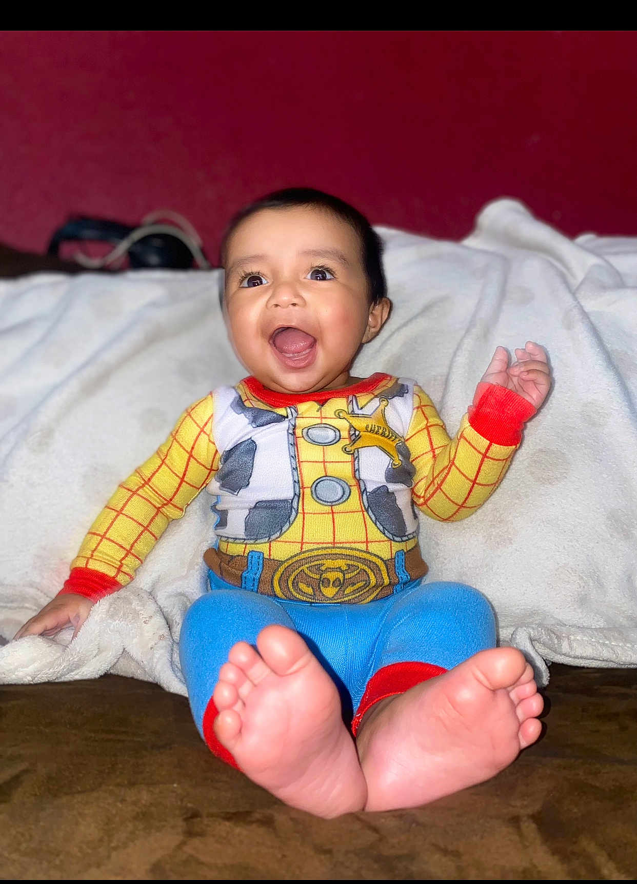 Ernest is registered to the contest to win money with this photo: baby, child, smiling, happy, indoors, clothing, colorful, cowboy, outfit, feet, toes, blanket, sitting, face, cute, portrait, person, expression, warm, cozy