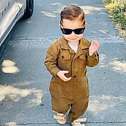 Emiliano is registered to the contest to win money with this photo: car, casual_clothing, child, cute, fashion, grass, hair, jumpsuit, outdoor, pavement, portrait, sandals, shadow, sidewalk, smile, street, sunglasses, sunny, toddler, walking