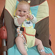 Astrid participe au concours pour gagner de l'argent avec cette photo : baby, smiling, clapping, baby_chair, bib, hospital_wristband, indoor, colorful, infant, cute, comfort, playful, child, person, foot, hand, face, happy, seat, fabric