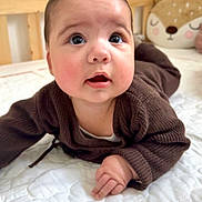 Lyana a rejoint le concours — aidez-le/la à gagner de superbes lots ! baby, infant, child, bed, quilt, brown_clothing, plush_toy, deer_pillow, cute, indoors, portrait, laying_down, curious_look, face, skin, hand, furniture, soft_lighting, cozy, home