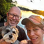 man, woman, dog, smile, glasses, hat, lake, sunset, water, trees, outdoor, nature, portrait, happy, pet, animal, casual, people, reflection, scenic