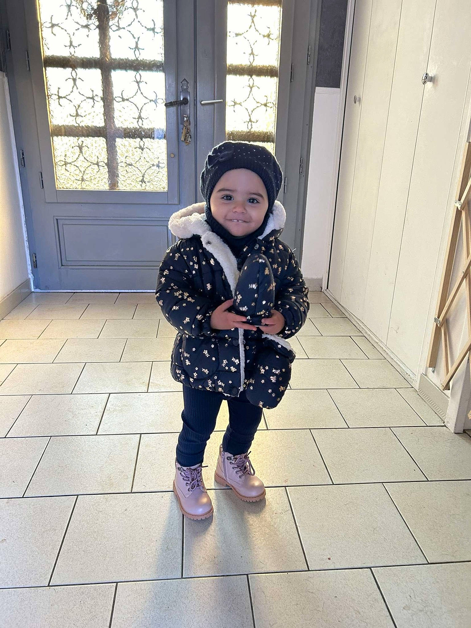Pearl participe au concours pour gagner de l'argent avec cette photo : baby, baby_toddler_clothing, child, door, electric_blue, floor, flooring, fun, happy, headwear, human_body, human_leg, joy, pattern, person, shadow, shoe, sleeve, sneakers, standing