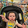 Locklynn is registered to the contest to win money with this photo: baby, child, car_seat, grocery_store, aisle, cereal_boxes, person, bib, clothing, shopping, indoor, retail, shelf, food, expression, reaching_hand, face, seatbelt, woman, glasses
