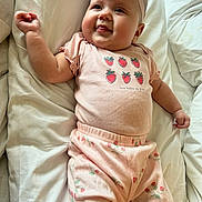 Maci joined the competition — help win amazing prizes! baby, infant, headband, flower, strawberry, pink_outfit, smile, chubby_cheeks, bed, blanket, lying_down, cute, portrait, onesie, pajamas, soft_lighting, hand, eyes, happy, skin