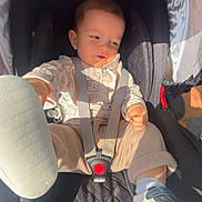 Ezio participe au concours pour gagner de l'argent avec cette photo : baby, car_seat, child, infant, footwear, shoe, straps, safety_harness, cute, clothing, pattern, bear, light, sunlight, expression, face, hand, leg, comfort, seat