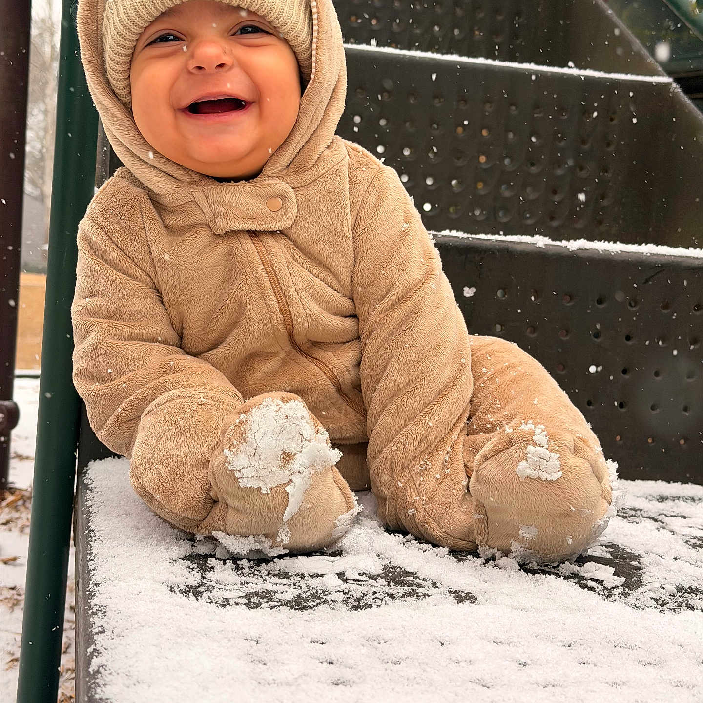 Liam is registered to the contest to win money with this photo: baby, child, snow, winter_clothing, snowsuit, hat, smile, playground, slide, snowfall, happy, cute, outdoor, cold_weather, infant, frozen, winter, clothing, person, joyful