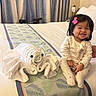 Raeyaa Jhade joined the competition — help win amazing prizes! baby, toddler, smiling, bed, towel_art, octopus, pink_bow, pajamas, indoor, curtains, blanket, bedroom, happy, cute, child, person, soft_lighting, floor_lamp, decor, playful