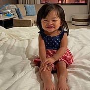 Raeyaa Jhade joined the competition — help win amazing prizes! toddler, child, smiling, bed, white_bedspread, dress, stars, stripes, indoor, living_room, couch, pillow, curtain, window, foot, hair, person, happy, sitting, home
