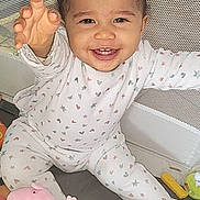 Lya participe au concours pour gagner de l'argent avec cette photo : baby, child, smiling, pajamas, toy, peppa_pig, mickey_mouse, playpen, mesh, indoor, happy, cute, infant, sitting, reaching, colorful, plush_toy, floor, childrens_toy, young_child