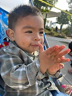 Aaron is registered to the contest to win money with this photo: baby, cheek, child, finger, food, forehead, fun, gesture, hand, happy, leisure, nose, pattern, person, plaid, plant, smile, tartan, thumb, toddler