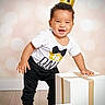 toddler, child, smiling, crown, birthday, gift_box, white_box, black_pants, white_shirt, indoor, floor, happy, standing, celebration, party, one_year_old, cute, posing, boy, photography
