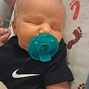 Axel is registered to the contest to win money with this photo: baby, pacifier, sleeping, blanket, footprint_pattern, onesie, black_clothing, infant, child, indoor, cute, peaceful, rest, soft_texture, head, face, small_hand, bed, fabric, comfort