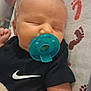 baby, pacifier, sleeping, blanket, footprint_pattern, onesie, black_clothing, infant, child, indoor, cute, peaceful, rest, soft_texture, head, face, small_hand, bed, fabric, comfort