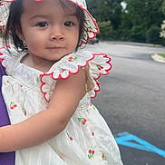 Scarlette is registered to the contest to win money with this photo: child, clothing, curious, cute, daylight, dress, face, fashion, hat, headwear, holding, nature, outdoor, parking_lot, person, smiling, summer, toddler, trees, young_child