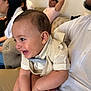 baby, child, infant, smiling, laughing, person, adult, clothing, vest, bow_tie, white_shirt, indoor, couch, furniture, people, family, happy, casual, seated, living_room