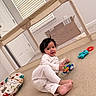 baby, child, indoor, playpen, toy, pajamas, floor, cushion, window, smile, face, person, home, carpet, door, light, colorful, cute, happy, infant