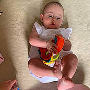 Phoebe-Lin is registered to the contest to win money with this photo: baby, child, toy, carpet, floor, hand, legs, white_clothing, infant, play, colorful, person, skin, foot, fingers, indoor, cute, young_child, curious, holding