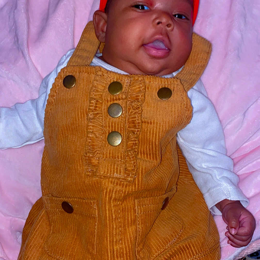 Jazelle is registered to the contest to win money with this photo: baby, bodypart, bonnet, cap, clothing, coat, couch, face, furniture, happy, hat, head, hood, jacket, knitwear, pants, person, photography, portrait, sweater
