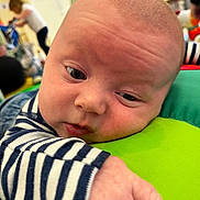 Arthur joined the competition — help win amazing prizes! baby, infant, close_up, face, hand, striped_clothing, green_cushion, indoor, child, person, curious, resting, soft_light, background_blur, people, casual, expression, young_child, early_childhood, candid