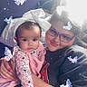 baby, child, glasses, headband, butterflies, sparkles, floral_clothing, pink, smile, portrait, indoor, light, cuddling, family, toddler, cozy, sitting, face, person, glowing_effect