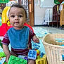 baby, child, toy, building_block, play_mat, bib, basket, crib, indoor, daycare, colorful, wall_mural, floor, expression, drool, sitting, curious, clothing, person, play