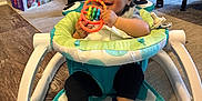 Ronan is registered to the contest to win money with this photo: baby, walker, toy, indoor, smile, child, clothing, floor, carpet, furniture, socks, head, face, play, happy, seat, colorful, infant, person, living_room
