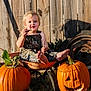 toddler, child, wheelbarrow, pumpkin, jack_o_lantern, outdoor, grass, wooden_fence, sunlight, plant, green_leaves, smiling, barefoot, rusty, fall, harvest, cute, nature, garden, playful