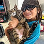Lilo is registered to the contest to win money with this photo: arm, cat, child, clothing, couch, expression, face, floor, furniture, hair, happy, holding, indoor, paw, person, smiling, sunglasses, tabby_cat, toy, window