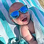 baby, beach, child, closeup, cute, fun, happy, infant, outdoor, reflection, relaxing, shiny, skin, smile, striped, summer, sunglasses, sunlight, towel, wrapped