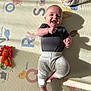 baby, infant, playmat, toy, blanket, smiling, happy, indoor, child, crawling_mat, clothing, foot, hand, face, shadow, light, animal_toy, colorful, pattern, cute