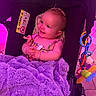 Antonia is registered to the contest to win money with this photo: baby, child, infant, smiling, car_seat, stroller, toy, teether, blanket, purple, magenta_lighting, indoor, portrait, sitting, happy, face, hands, clothing, airbag_label, playtime