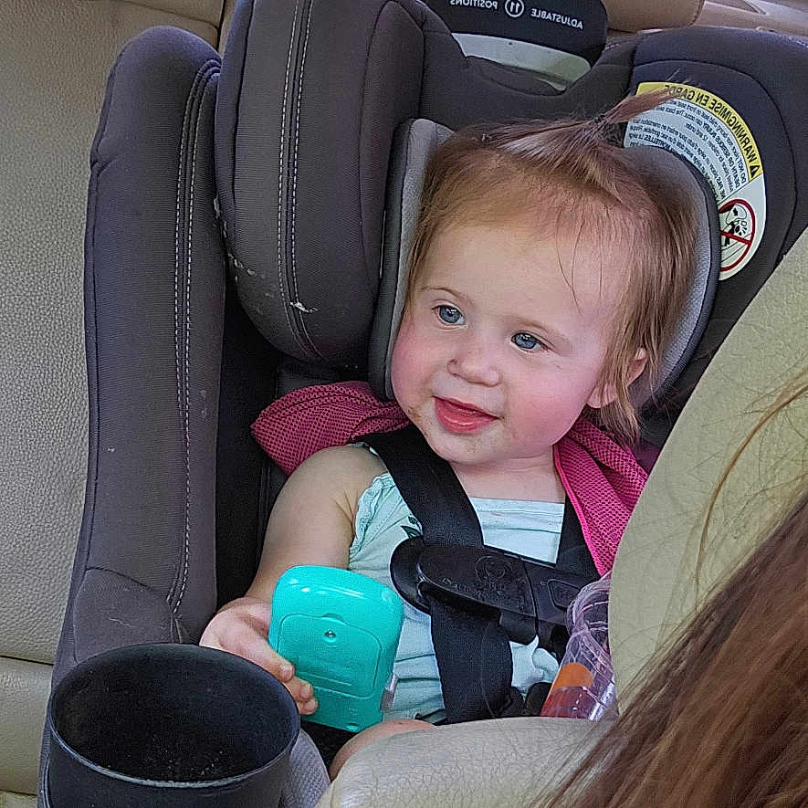 Raylenn joined the competition — help win amazing prizes! toddler, car_seat, child, toy, blue, car_interior, seatbelt, smiling, hair, pony_tail, window, daylight, backseat, human, person, clothing, seat, safety, happy, automobile