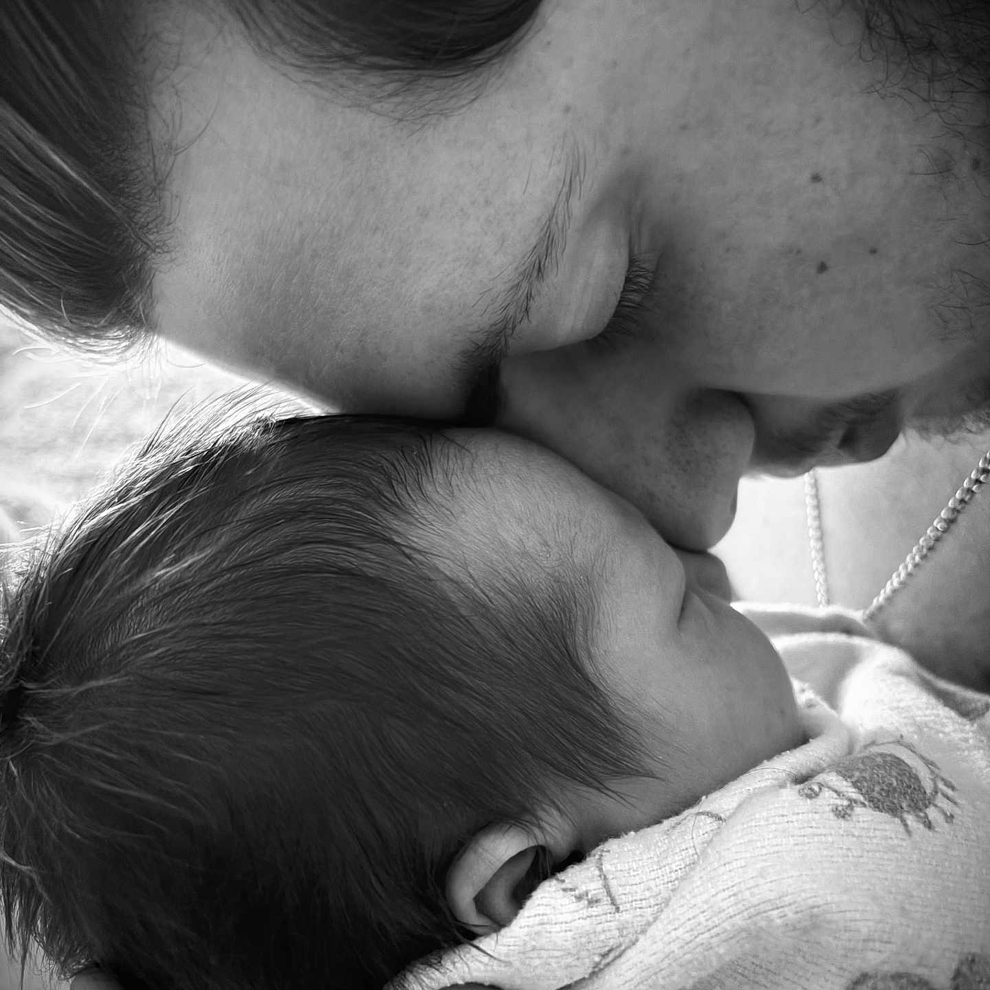 Arlo is registered to the contest to win money with this photo: newborn, baby, parent, mother, father, family, kiss, affection, tenderness, black_and_white, portrait, close_up, sleeping, infant, hand, embrace, bonding, blanket, love, photography