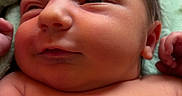 Arlo is registered to the contest to win money with this photo: newborn, baby, infant, child, face, portrait, lying_down, blanket, green_blanket, indoors, close_up, bare_skin, eyes_open, serious_expression, hands, head, torso, soft_lighting, home, photography