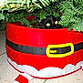 Aston participe au concours pour gagner de l'argent avec cette photo : cat, black_cat, christmas_tree, tree_skirt, holiday, indoor, pet, yellow_eyes, pine_branches, festive, curious, hiding, floor_tiles, red, green, seasonal, decor, animal, cute, playful