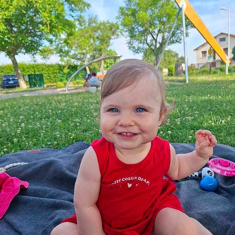 Charlie participe au concours pour gagner de l'argent avec cette photo : baby, blanket, blue_sky, child, cute, daytime, grass, greenery, happy, infant, nature, outdoor, park, playful, portrait, red_clothing, sitting, smiling, sunny, toy