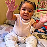 baby, child, infant, smiling, sitting, bedroom, bed, blanket, pajamas, curly_hair, hands, feet, portrait, indoor, home, warm_lighting, colorful, framed_picture, bedroom_decor, happy