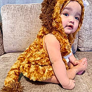 Ethan Mori is registered to the contest to win money with this photo: baby, child, lion_costume, costume, plush, couch, indoor, cute, portrait, sitting, face, headwear, fur, animal_costume, expression, hands, feet, soft_texture, furniture, curious